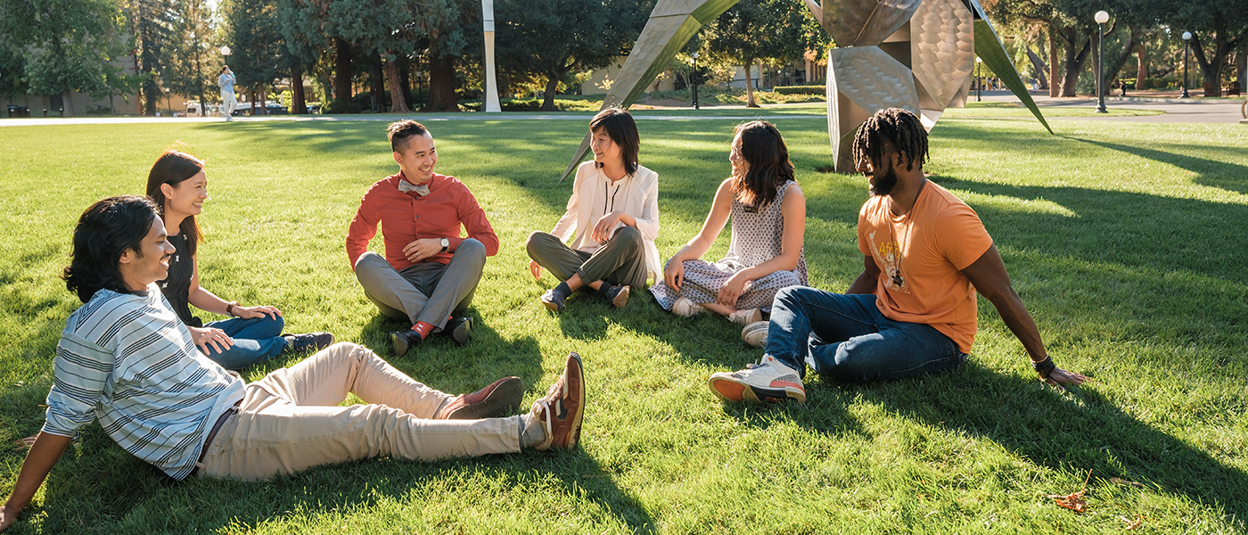 Photo of a group of students laughing in front of a water fountain.