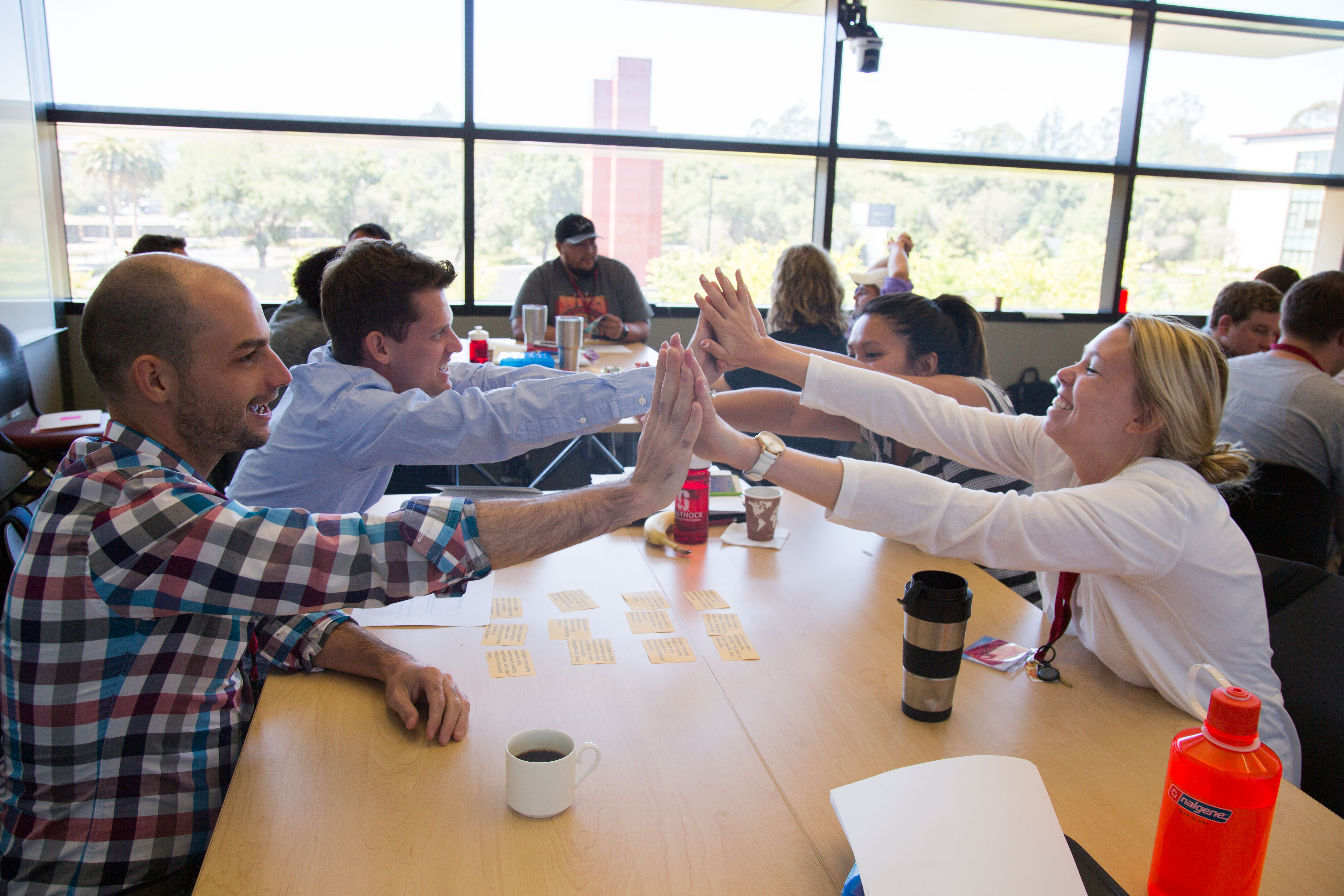 Photo of people around the table give a group high-five