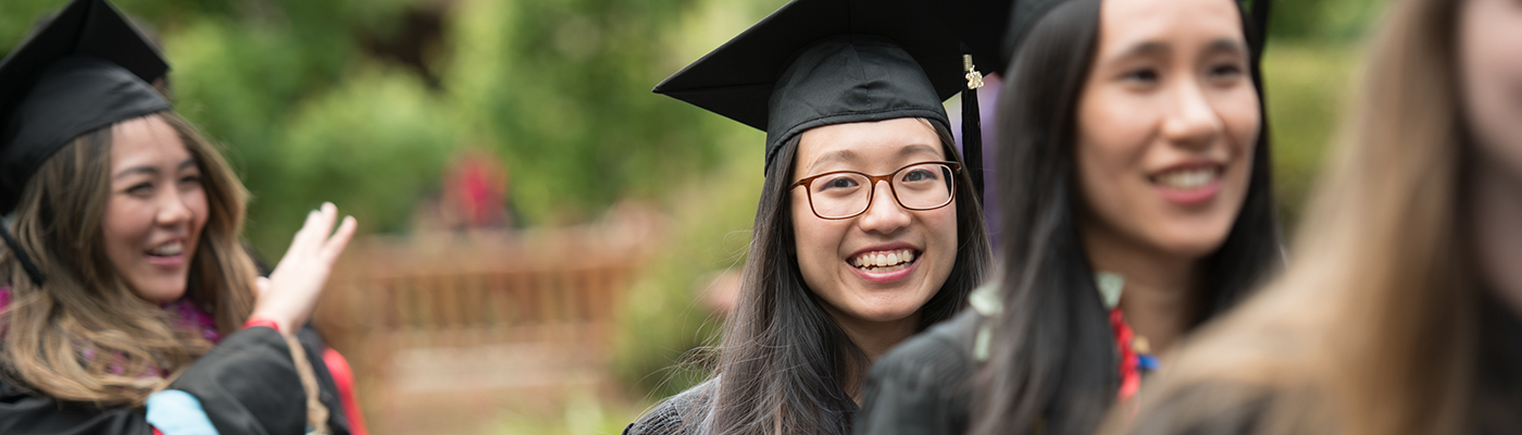 Photo of smiling student amongst her classmates during graduation walk.