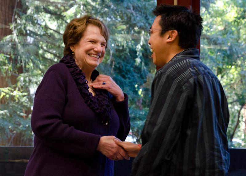 A female and male shaking hands and smiling