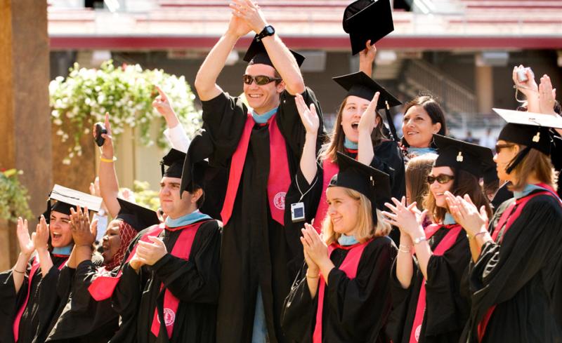 Graduating students cheering at ceremony.