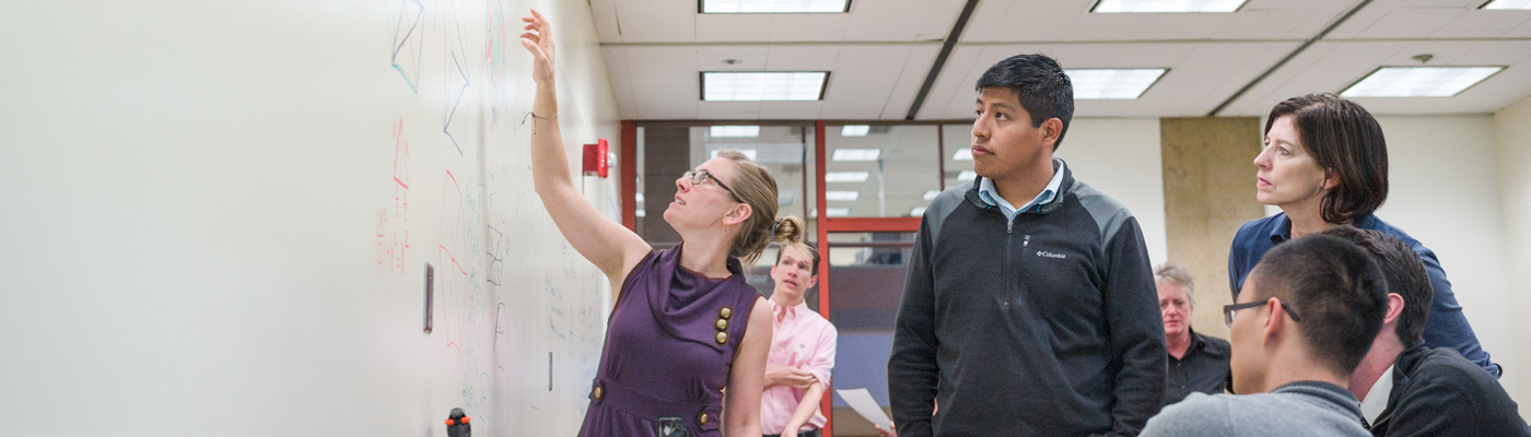 Photo of a group of people working on a whiteboard.