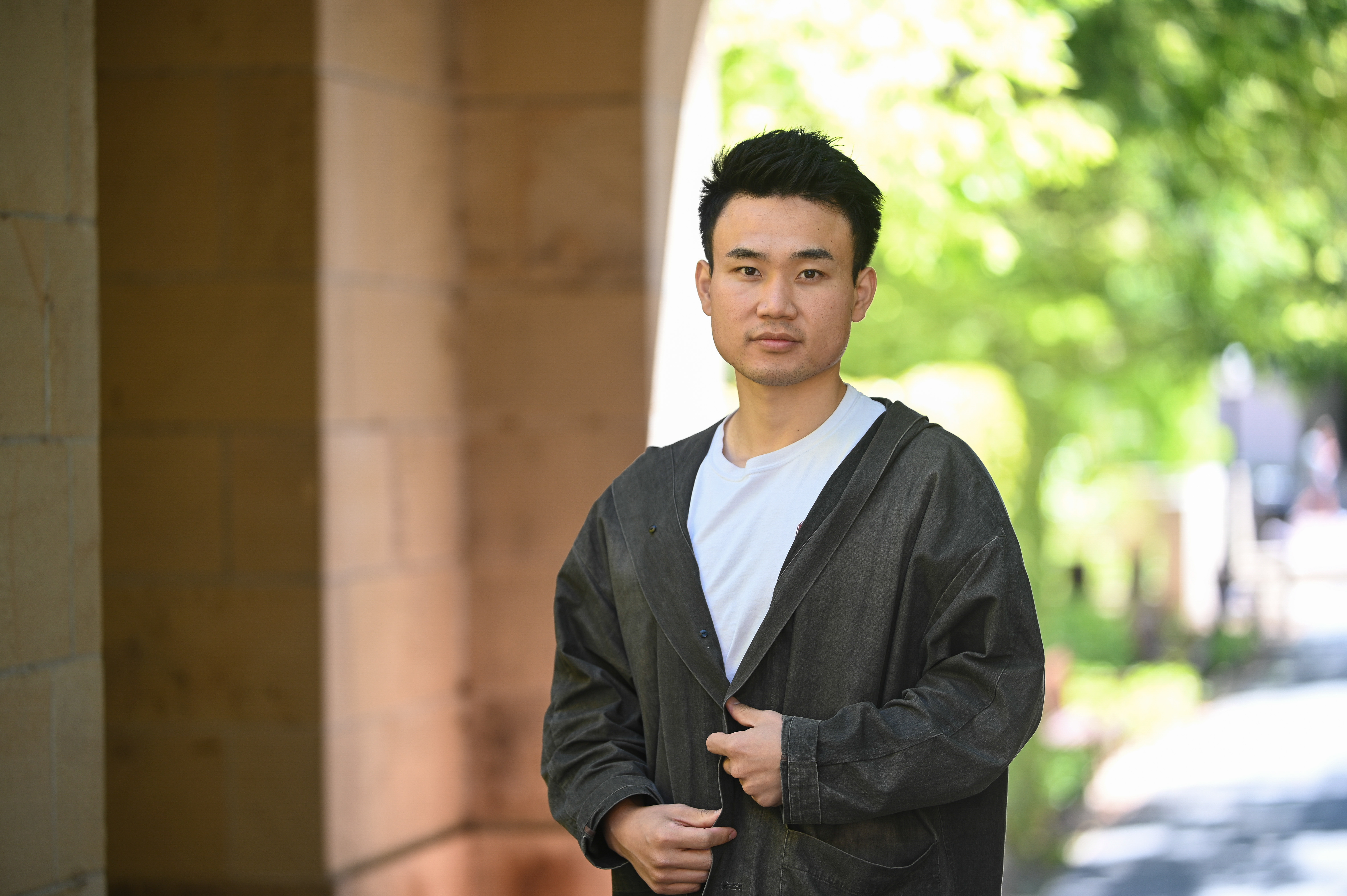 Photo of Haoran "Elvis" Wu standing under a Stanford arch