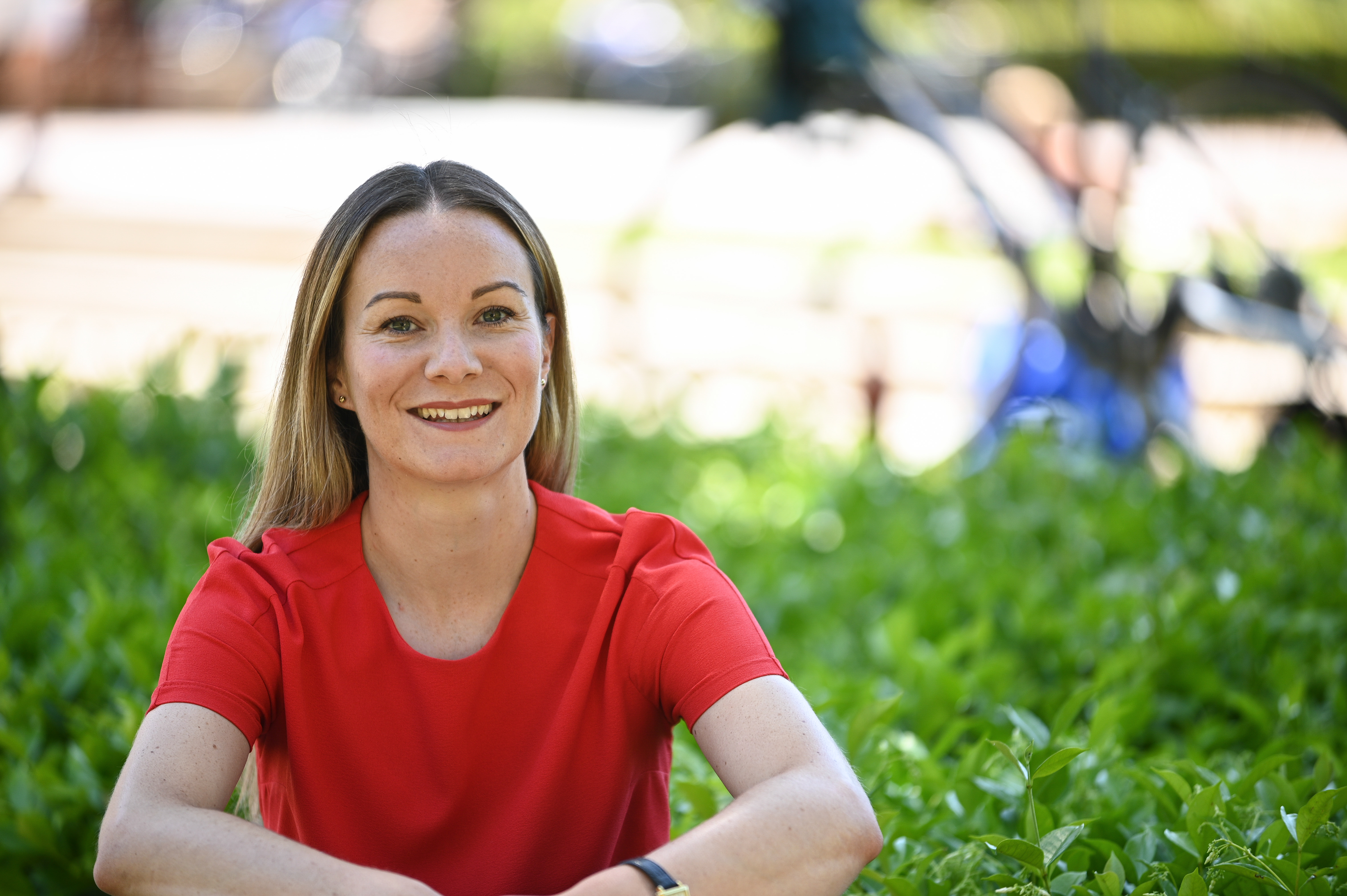 Photo of Jennifer Fortet sitting outside, with the suggestion of a bike behind her