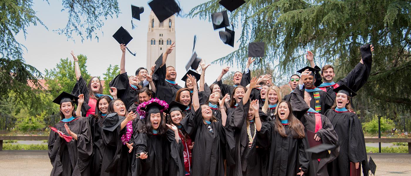 Group of graduating students in their gowns throwing their caps in the air.