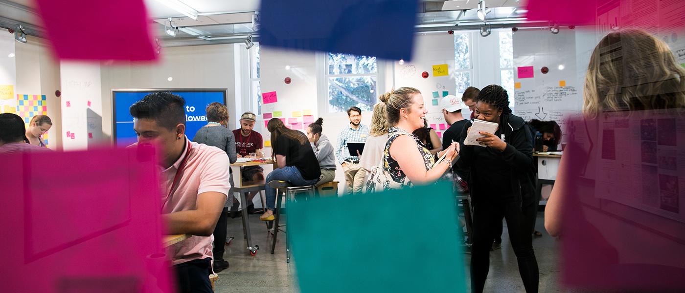 Looking into a workshop full of attendees through a window with sticky notes on it.