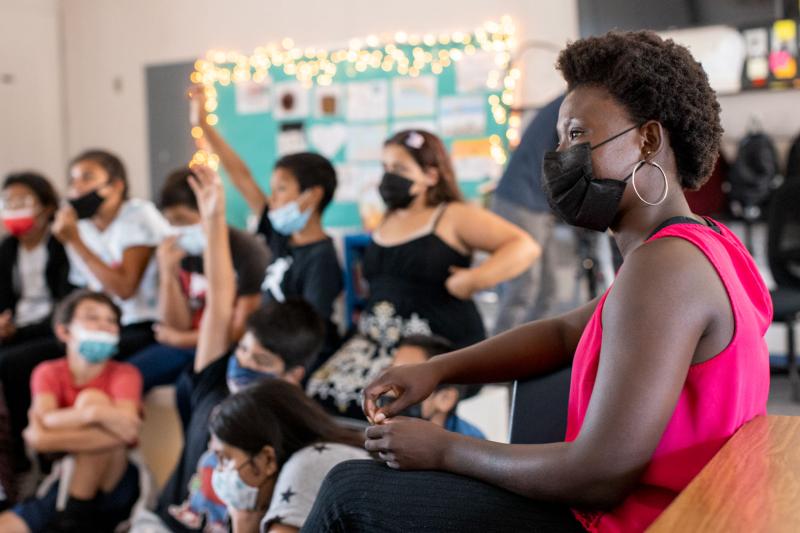 A teacher in a classroom with kids on the background