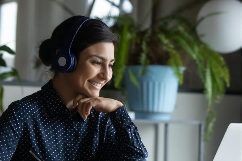 A woman wearing headphones looking at laptop.