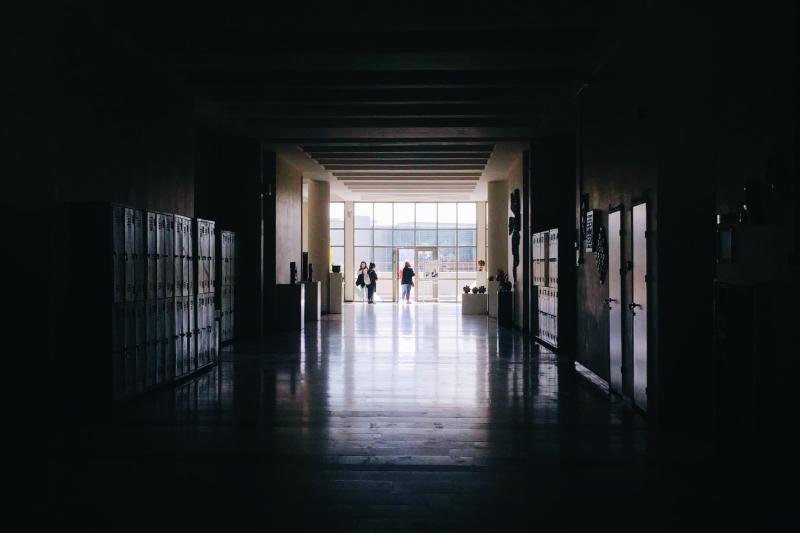 Photo of a dark school hallway opening into the light