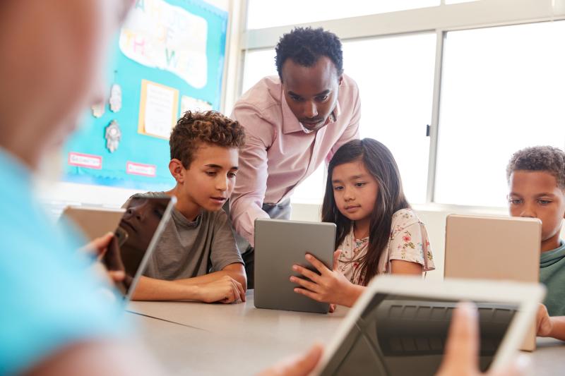 Picture of teacher with students looking at an ipad