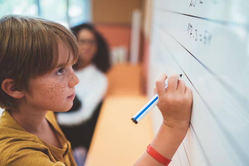 Photo of child doing math problem on a white board