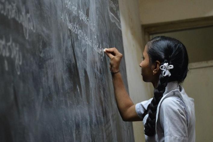 Photo of young woman writing on a chalkboard