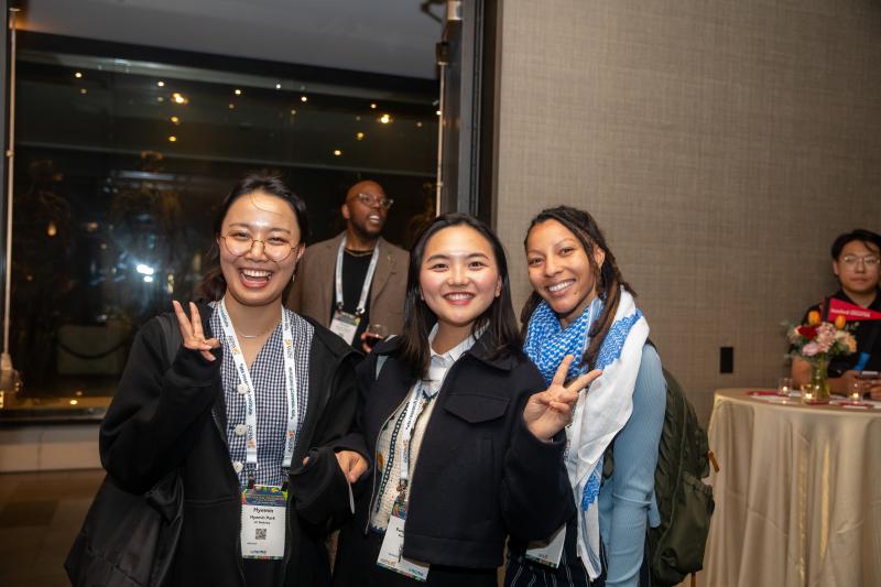 Students give peace signs and pose at an indoor reception