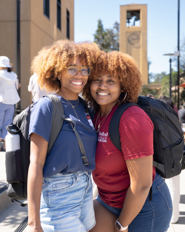 Two GSE students at the community picnic, with the Stanford clocktower behind them. (Photo: Joleen Richards)