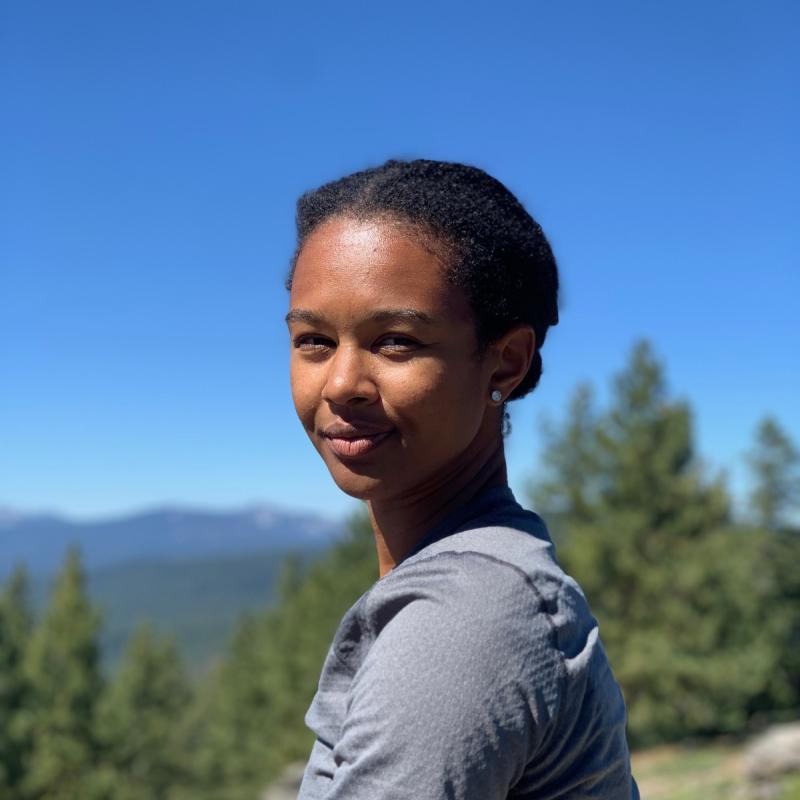 Photo of Savannah Strong, looking sideways at the camera, in a beautiful mountain setting