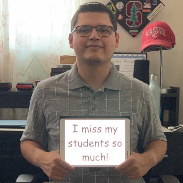 STEP student Luis A. Gonzalez holding an iPad with the message "I miss my students so much!"