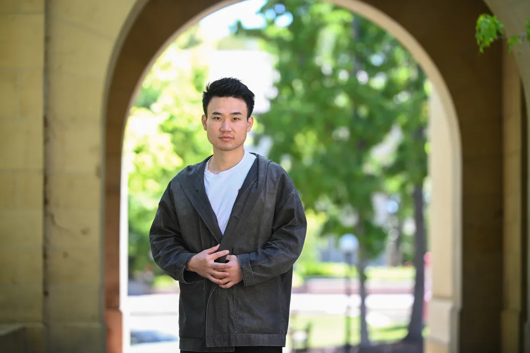 Photo of Haroan "Elvis" Wu standing under an arch with leafy trees in the background