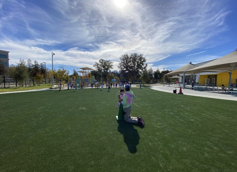 An educator and child on a green lawn