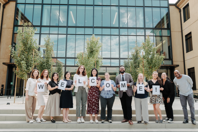 Picture of Academic Affairs team holding welcome sign at the steps of the Raikes building.