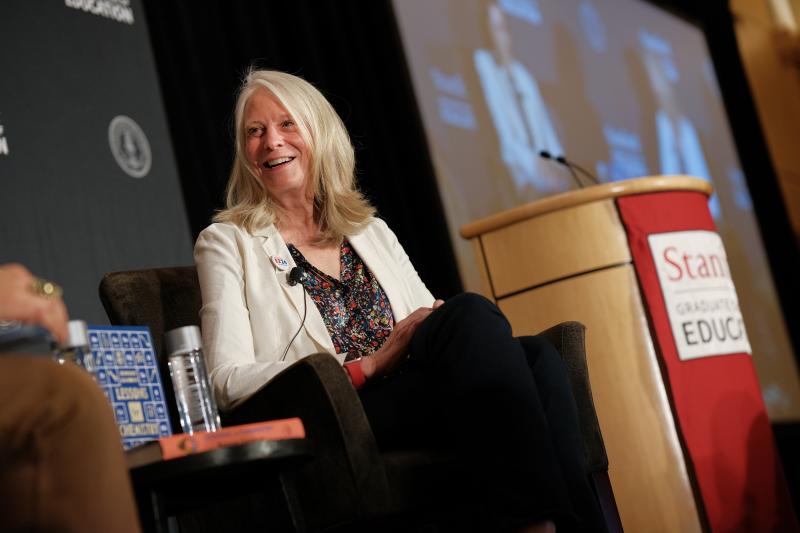 Picture of Bonnie Garmus sitting next to Stanford Graduate School of Education podium