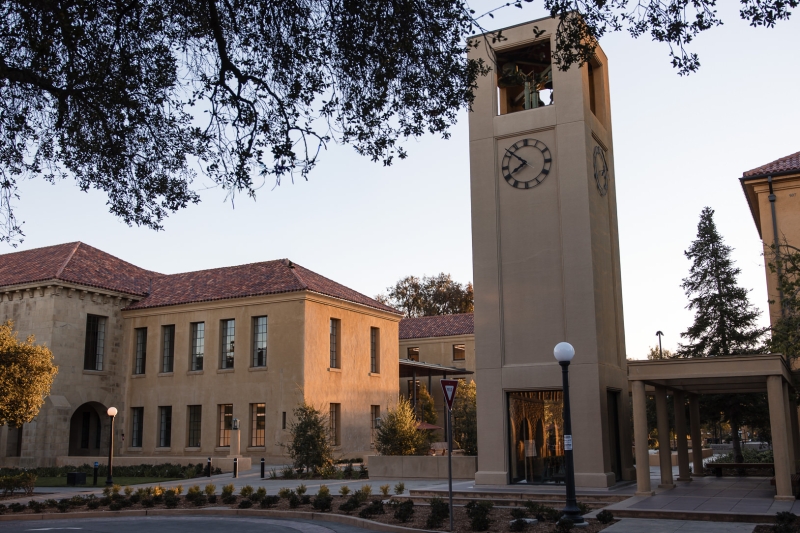 Picture of the GSE campus with the clock tower in the middle flanked by two buildings at sunset