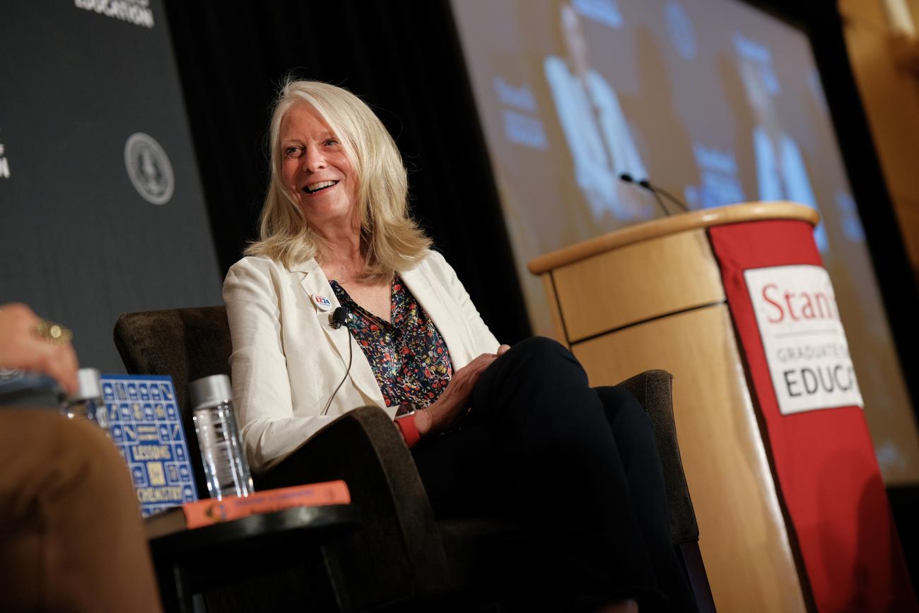 Picture of Bonnie Garmus sitting next to Stanford Graduate School of Education podium