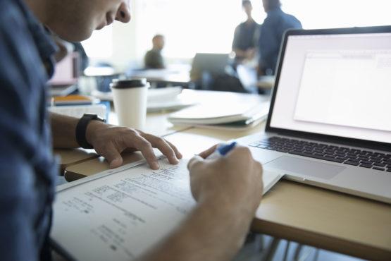 Photo of someone going over a set of test questions in front of a laptop.