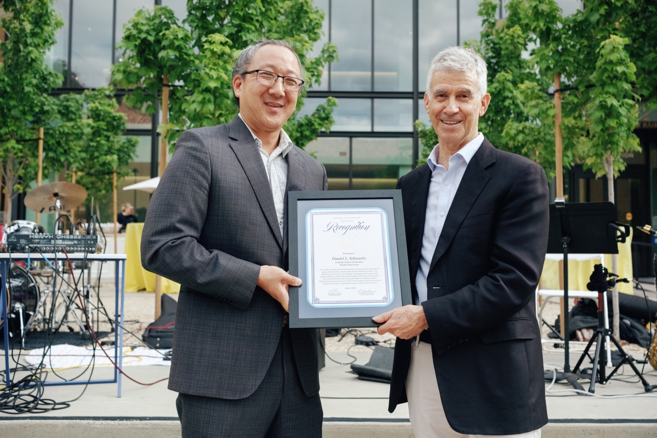 Two people pose with framed certificate