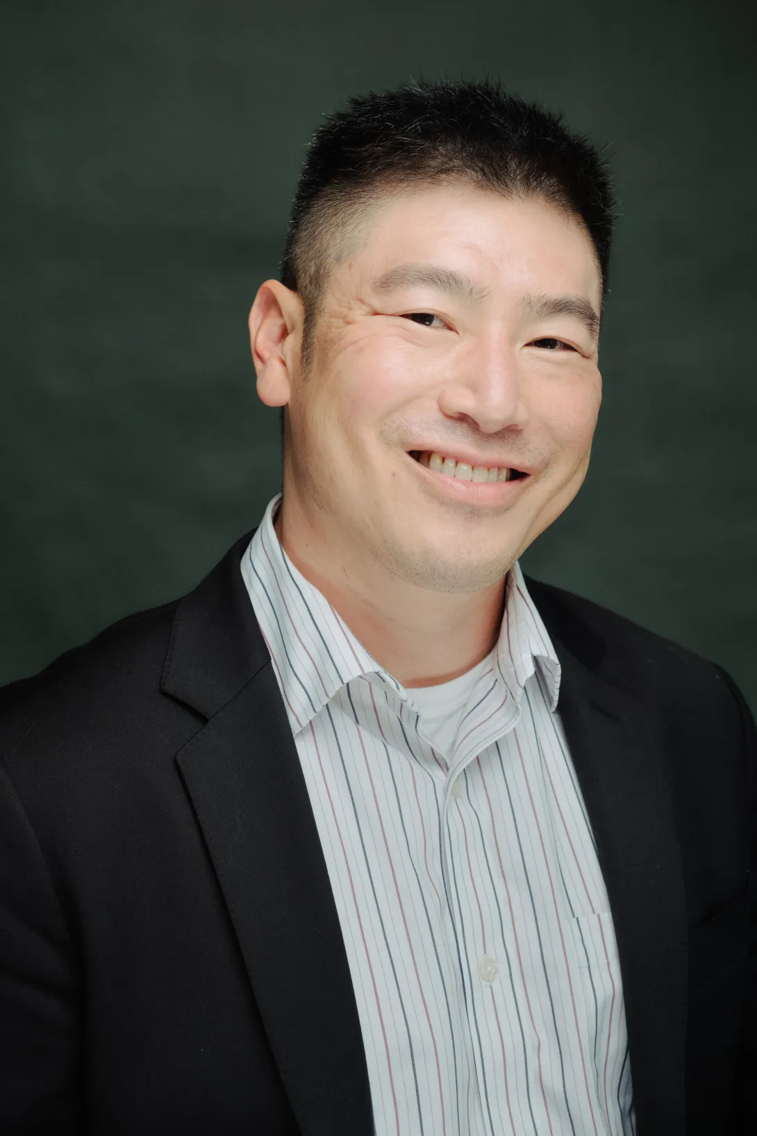 Picture of Victor Lee in a blazer, shirt, and in front of a dark background.